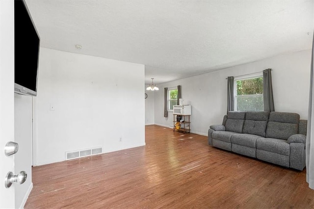 9021 E 79th St, Raytown, MO 64138 - living area with wood finished floors, a chandelier, and a textured ceiling