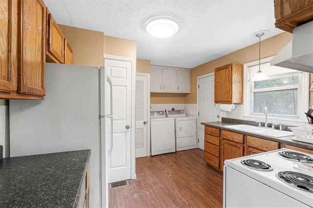 9021 E 79th St, Raytown, MO 64138 - kitchen featuring white appliances, wood finished floors, washing machine and dryer, brown cabinets, and dark countertops