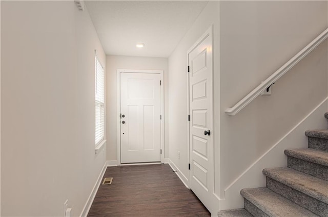 entryway with healthy amount of natural light, stairs, baseboards, and dark wood finished floors