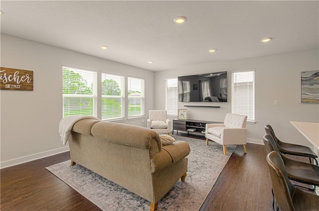 living area with baseboards, healthy amount of natural light, dark wood-type flooring, and recessed lighting