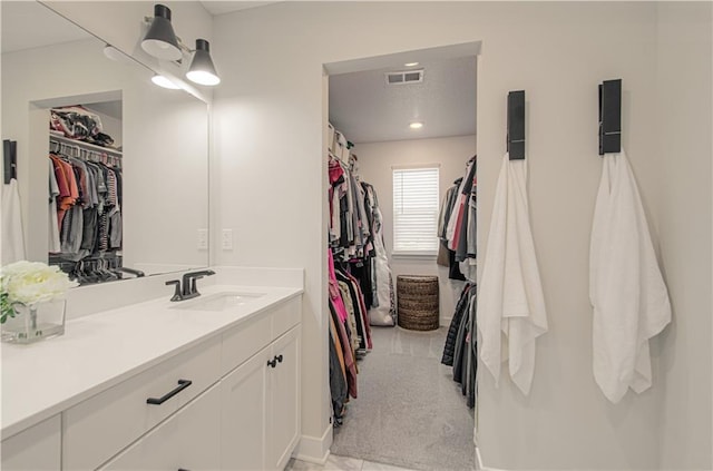 full bathroom with a walk in closet and vanity