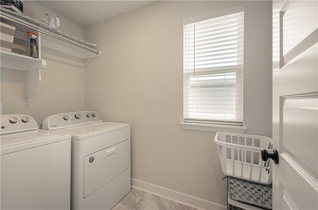 clothes washing area featuring washer and clothes dryer, baseboards, and light marble finish floors