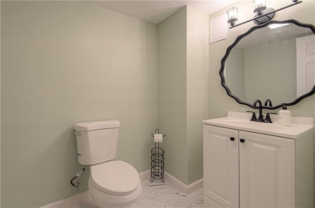 bathroom featuring baseboards, toilet, marble look tile flooring, a textured ceiling, and vanity