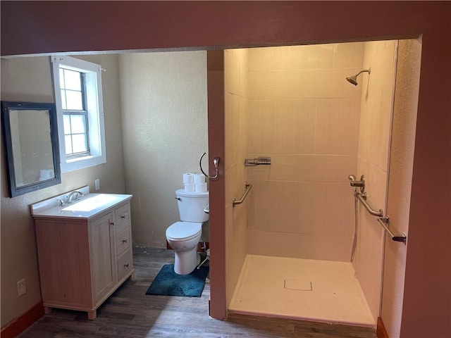 bathroom with wood finished floors, a stall shower, toilet, and vanity