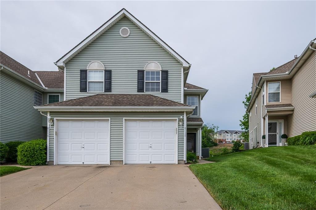 8008 NE Elmwood Ave, Kansas City, MO 64119 - traditional home featuring driveway, a front yard, a garage, and central air condition unit