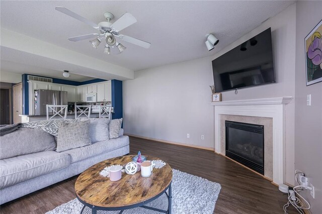 8008 NE Elmwood Ave, Kansas City, MO 64119 - living area featuring dark wood-style floors, baseboards, ceiling fan, and a glass covered fireplace