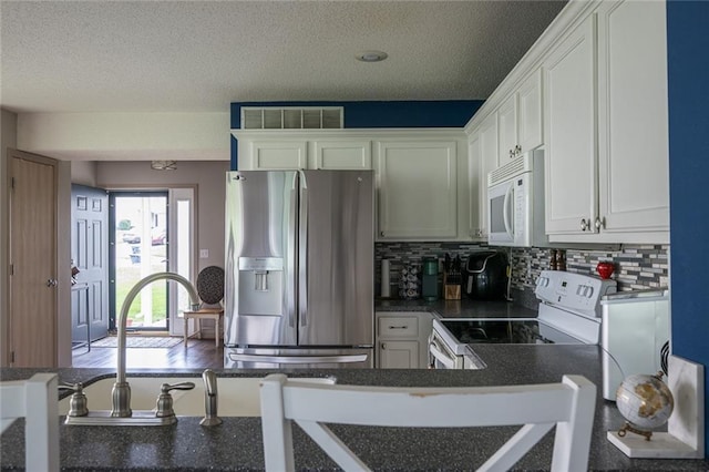 8008 NE Elmwood Ave, Kansas City, MO 64119 - kitchen with stainless steel fridge, white microwave, electric range, dark countertops, and decorative backsplash