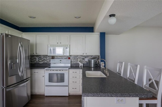 8008 NE Elmwood Ave, Kansas City, MO 64119 - kitchen with white appliances, a sink, a peninsula, dark countertops, and white cabinetry