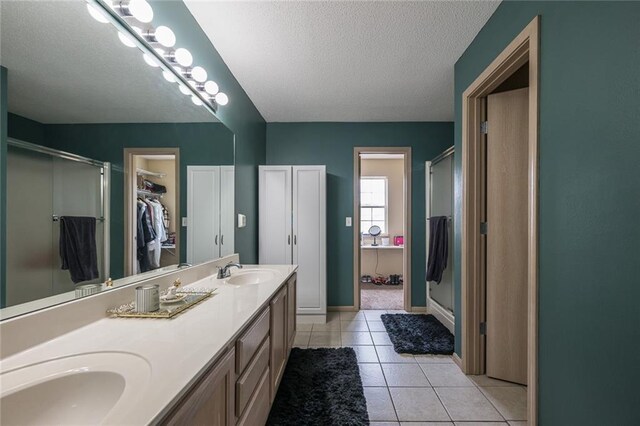 8008 NE Elmwood Ave, Kansas City, MO 64119 - bathroom featuring a stall shower, a textured ceiling, double vanity, a walk in closet, and tile patterned floors