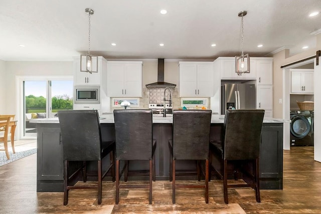 85 Birdie Ln, Mound City, KS 66056 - kitchen featuring wall chimney range hood, washer / clothes dryer, stainless steel appliances, a large island with sink, and light countertops