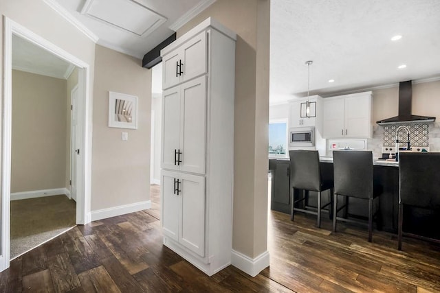 85 Birdie Ln, Mound City, KS 66056 - kitchen featuring wall chimney exhaust hood, stainless steel microwave, a kitchen breakfast bar, ornamental molding, and dark wood-style floors