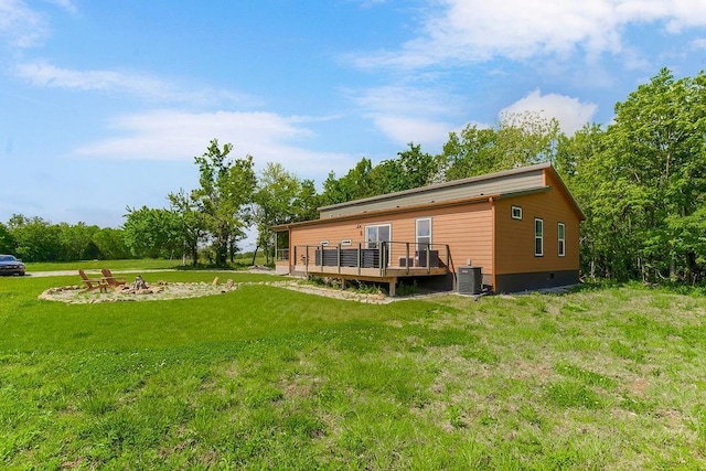 85 Birdie Ln, Mound City, KS 66056 - back of property with a wooden deck, a fire pit, cooling unit, and a yard