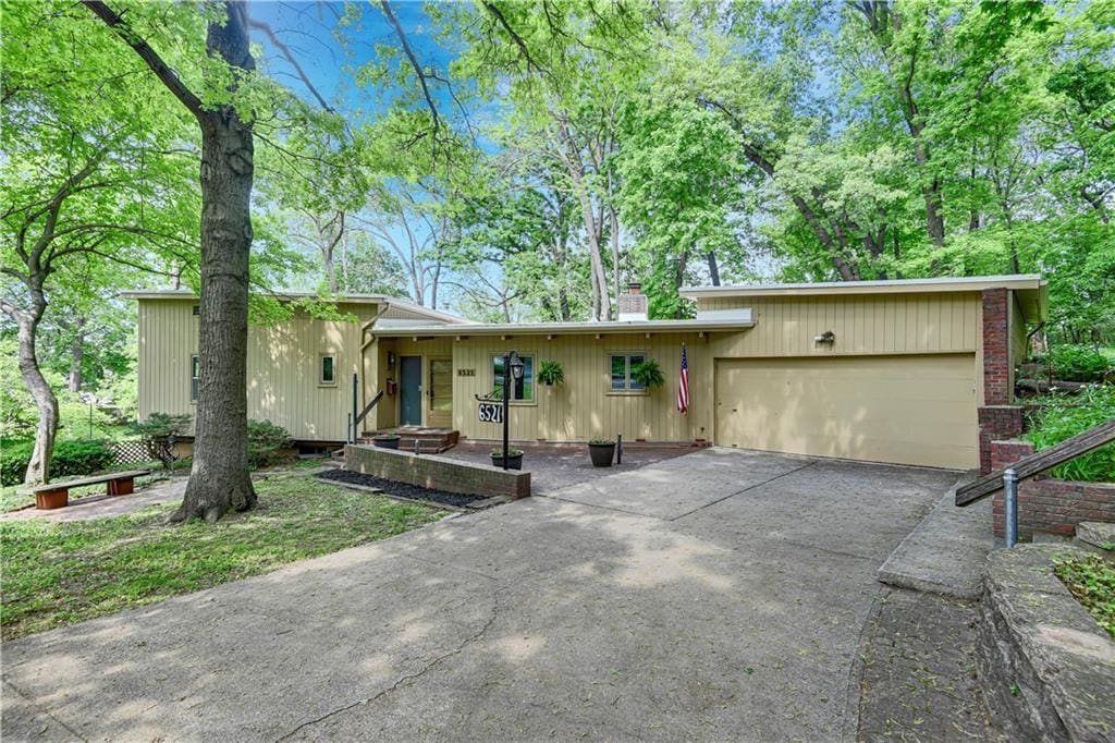 6521 Burnham Dr, Mission, KS 66202 - view of front of house with asphalt driveway, an attached garage, and a chimney