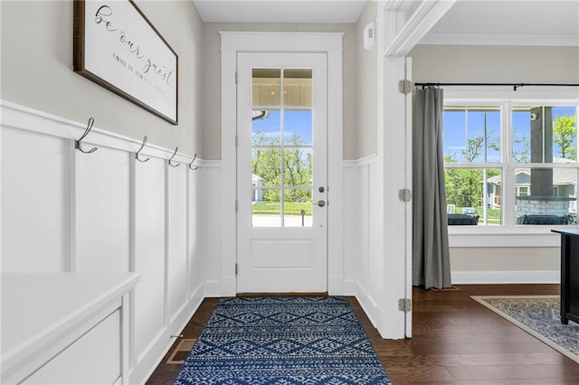 entryway featuring a decorative wall, wainscoting, dark wood-type flooring, and crown molding