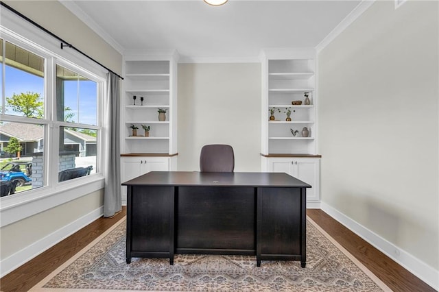 office area with dark wood finished floors, baseboards, ornamental molding, and built in shelves