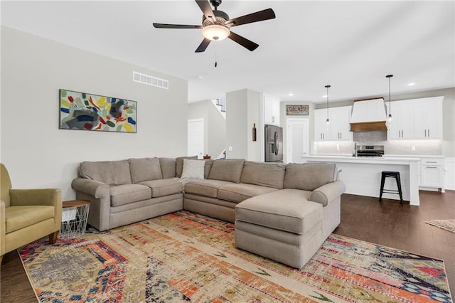 living area with wood finished floors, a ceiling fan, recessed lighting, and stairs