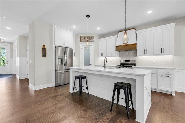 kitchen with stainless steel appliances, dark wood finished floors, a kitchen breakfast bar, light countertops, and decorative backsplash