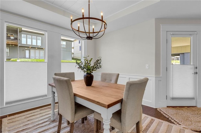 dining room featuring a chandelier, a wainscoted wall, wood finished floors, and a decorative wall