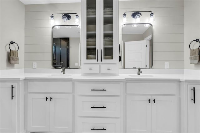 bathroom featuring double vanity, wooden walls, and a shower with door