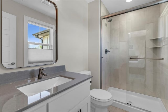 bathroom featuring a stall shower, toilet, and vanity