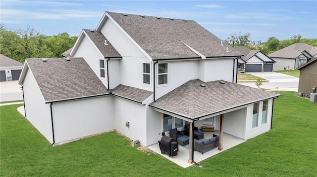 back of house with roof with shingles, a lawn, and a patio area