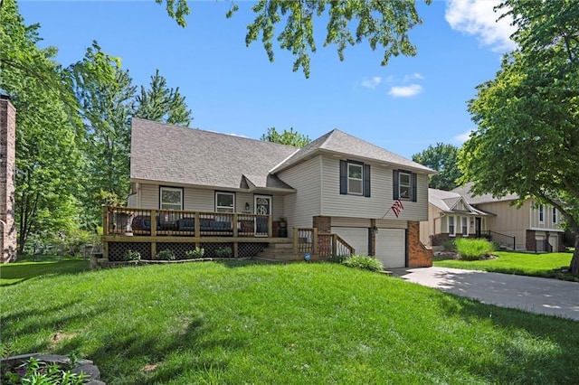 split level home featuring an attached garage, concrete driveway, a front yard, a wooden deck, and brick siding
