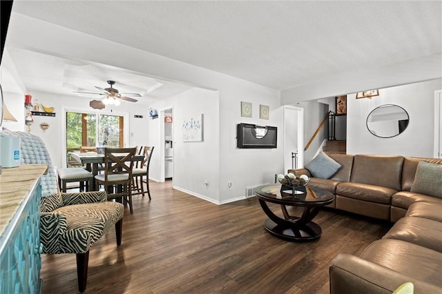 living room featuring dark wood-style flooring, baseboards, ceiling fan, stairs, and a textured ceiling
