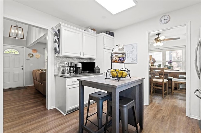 kitchen with wood finished floors, white cabinetry, a ceiling fan, and tasteful backsplash