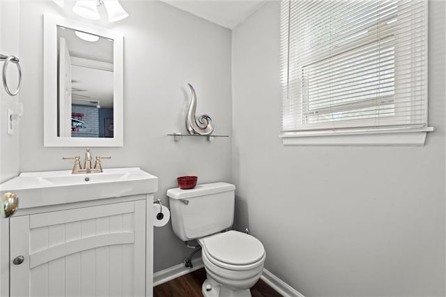 bathroom with toilet, wood finished floors, vanity, and baseboards