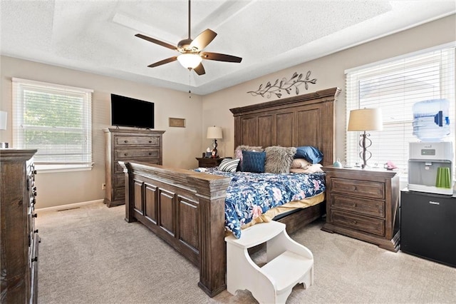 bedroom with light colored carpet, a textured ceiling, baseboards, and ceiling fan