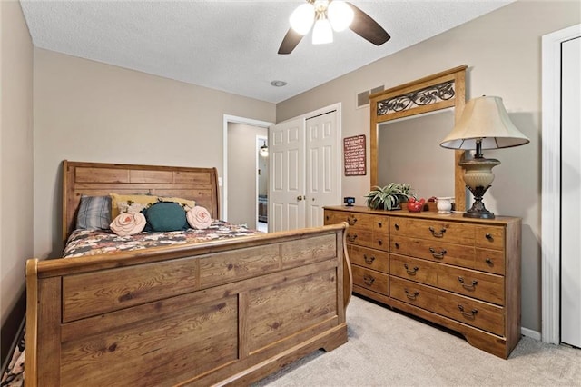 bedroom featuring light carpet, a ceiling fan, and a textured ceiling