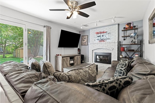living room featuring track lighting, ceiling fan, and a fireplace