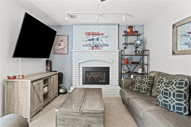 living room with light carpet, a fireplace, and rail lighting
