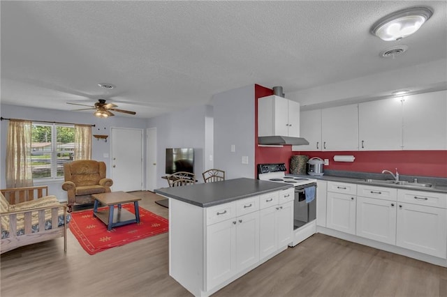 kitchen featuring white range with electric stovetop, a textured ceiling, a sink, dark countertops, and a peninsula