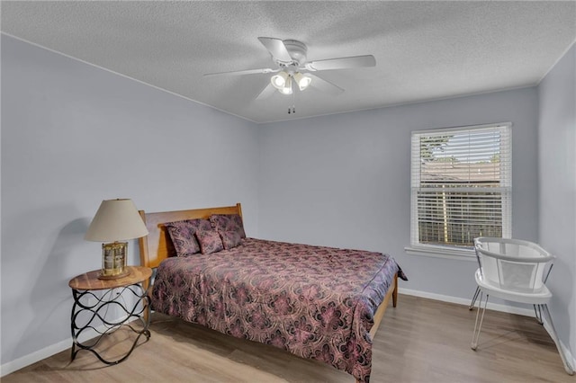 bedroom with wood finished floors, a textured ceiling, baseboards, and a ceiling fan