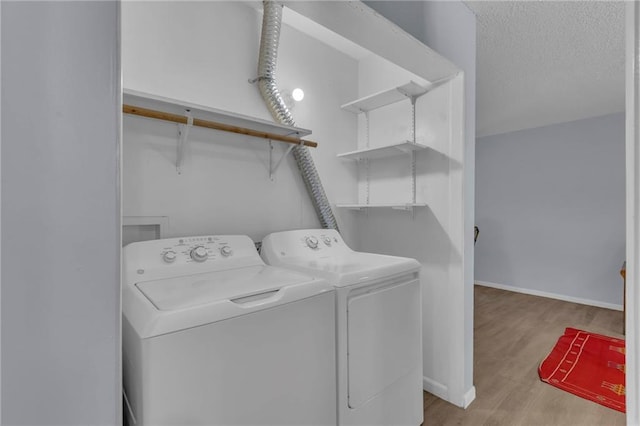 laundry area featuring washing machine and dryer, wood finished floors, baseboards, and a textured ceiling