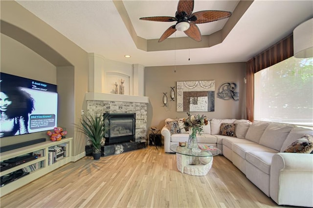 5445 NE Northgate Xing, Lees Summit, MO 64064 - living area featuring a tray ceiling, a ceiling fan, wood finished floors, and a fireplace