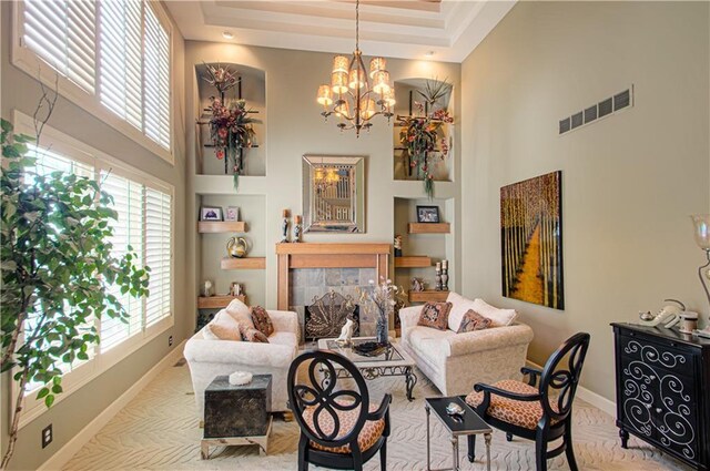 5445 NE Northgate Xing, Lees Summit, MO 64064 - living area with a towering ceiling, baseboards, a tiled fireplace, a tray ceiling, and a chandelier