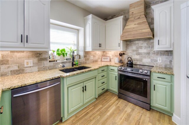 kitchen with appliances with stainless steel finishes, custom range hood, a sink, and white cabinets