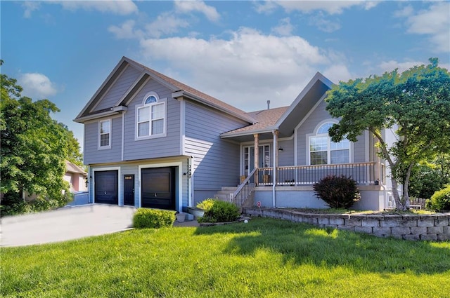 tri-level home with an attached garage, concrete driveway, a front yard, and covered porch