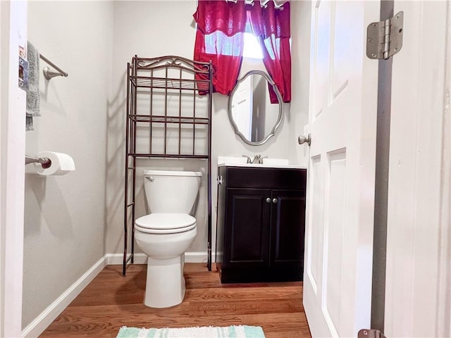 708 Cantebury Dr, Warrensburg, MO 64093 - half bathroom featuring toilet, wood finished floors, vanity, and baseboards
