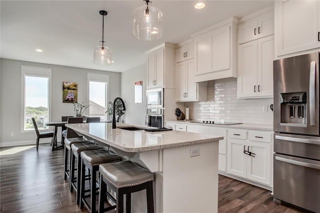 4713 NE Saratoga Ct, Lees Summit, MO 64064 - kitchen featuring appliances with stainless steel finishes, a kitchen island with sink, dark wood-style floors, decorative backsplash, and recessed lighting