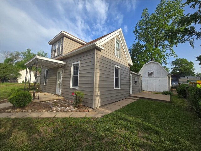 117 E Buford St, Wellington, MO 64097 - view of property exterior with a patio, a lawn, an outbuilding, and a shed
