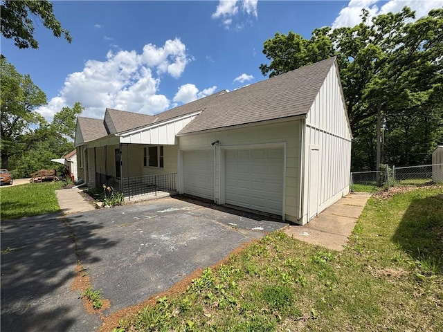 7115 Myrtle Ave, Kansas City, MO 64132 - view of side of home featuring a shingled roof, board and batten siding, and driveway