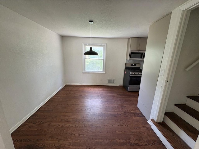 7115 Myrtle Ave, Kansas City, MO 64132 - unfurnished dining area with dark wood-style floors, stairway, baseboards, and a textured ceiling