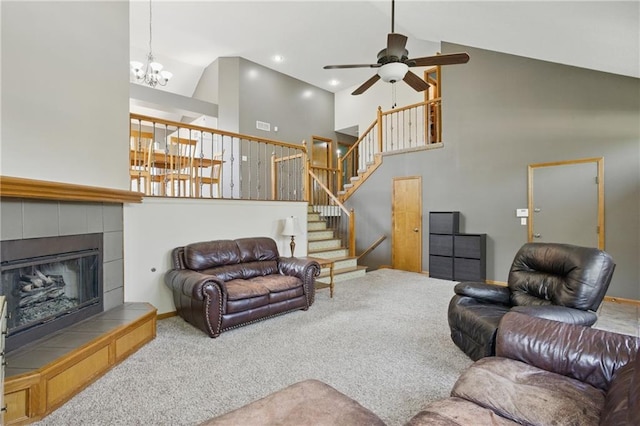 living area featuring high vaulted ceiling, carpet flooring, a ceiling fan, a tiled fireplace, and a chandelier
