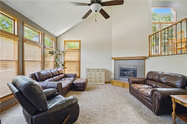 carpeted living room with ceiling fan, a tile fireplace, and high vaulted ceiling