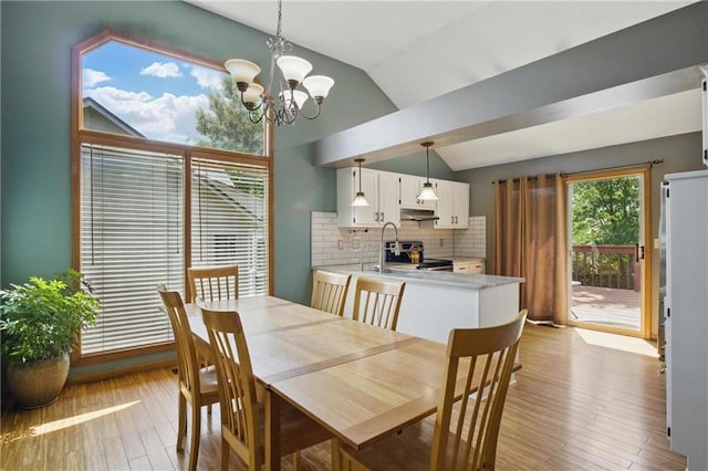 dining space featuring a chandelier, vaulted ceiling, and light wood-style flooring