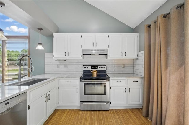 kitchen with appliances with stainless steel finishes, a sink, under cabinet range hood, vaulted ceiling, and light wood-style flooring