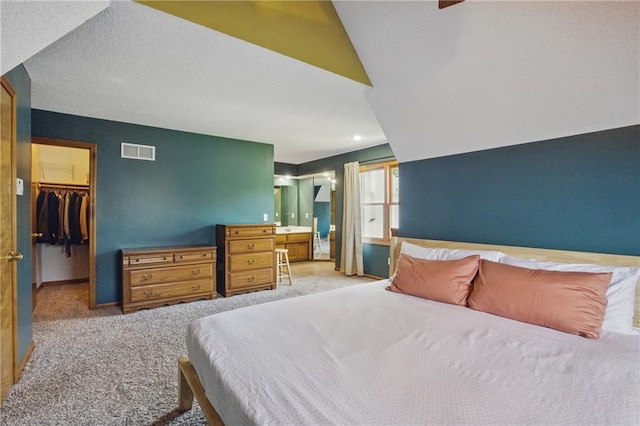 bedroom with carpet flooring, a walk in closet, a closet, and ensuite bathroom